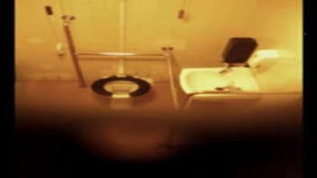 Une femme d'âge mûr se rend aux toilettes sans savoir qu'une petite caméra cachée filme la scène. Elle est capturée dans son intimité la plus totale, sans aucune idée qu'elle est observée.
